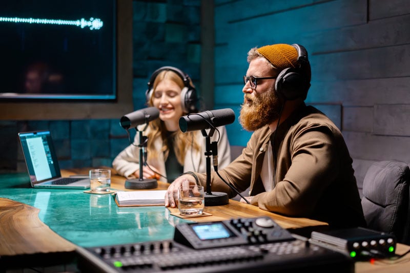 uomo con la barba e una donna fanno un podcast